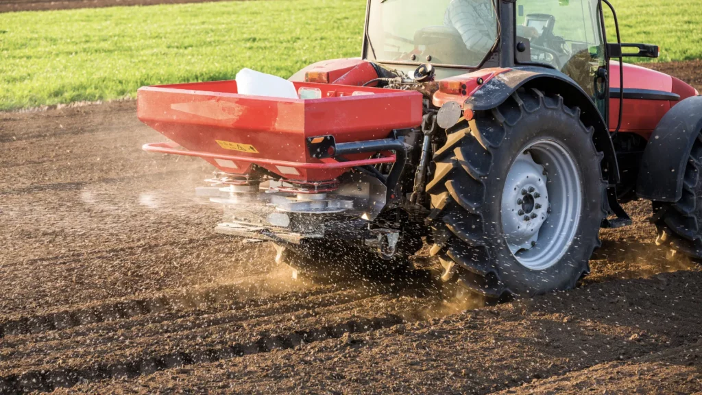 Machine épandant des engrais dans un champ, illustration de l’impact du MACF sur les engrais et les coûts agricoles